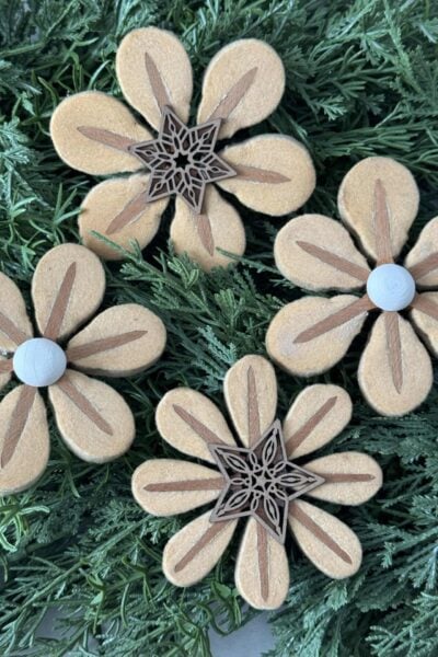 Four flowers made out of piano hammers laying on greenery.