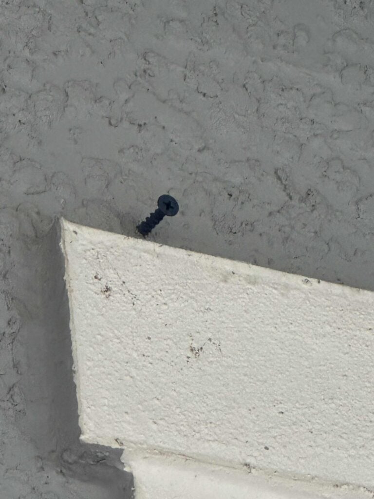 A masonry screw sticking out 1/2 inch  from the house, to be used to hang Christmas garland. 