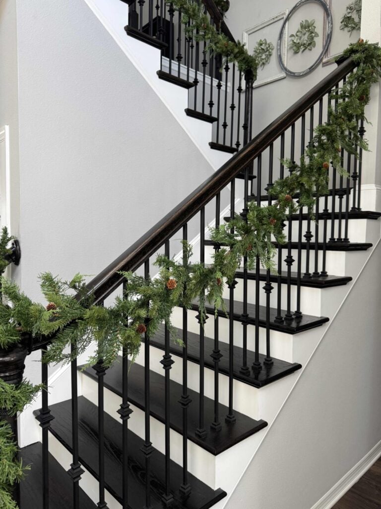 An evergreen garland hanging on a staircase. 