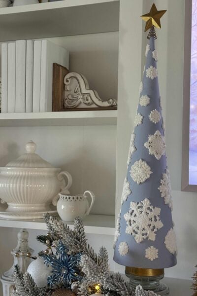 A blue cone Christmas tree covered with white air-dry clay snowflakes.