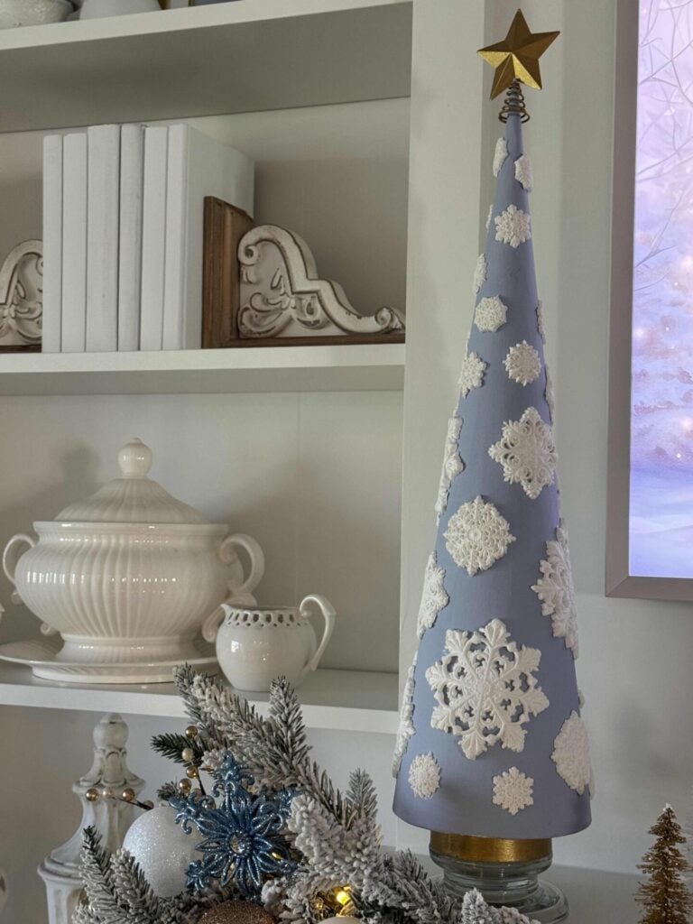 A blue cone Christmas tree with white snowflakes and a gold star on top. 