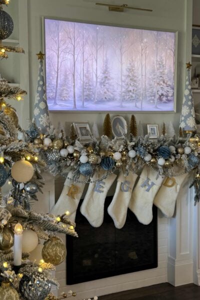 A white mantel decorated with blue, gold, and white for Christmas.