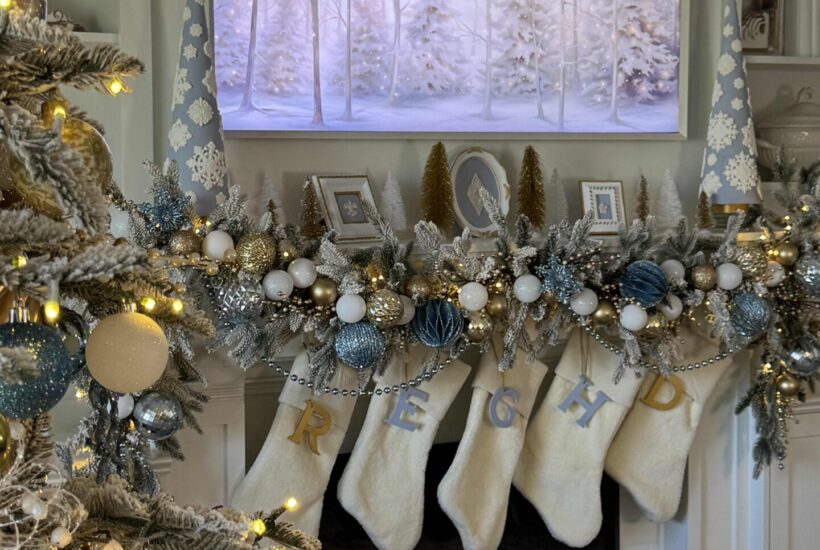 A white mantel decorated with blue, gold, and white for Christmas.
