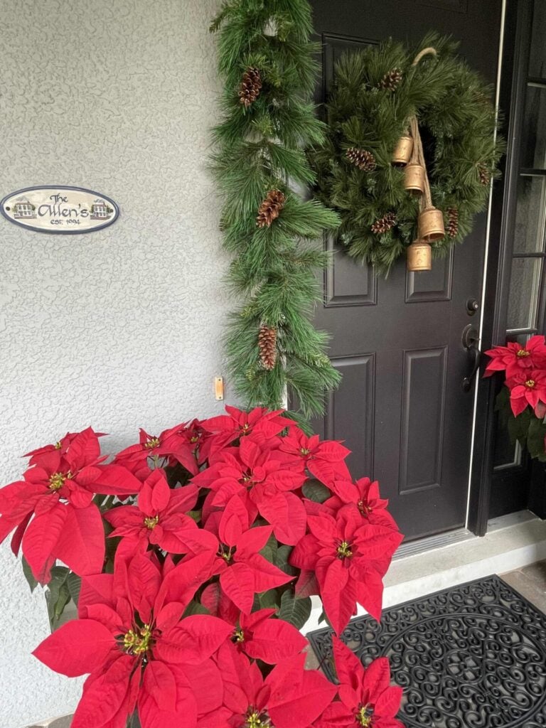 A garland and wreath with pinecones and antique bells on a black door. 