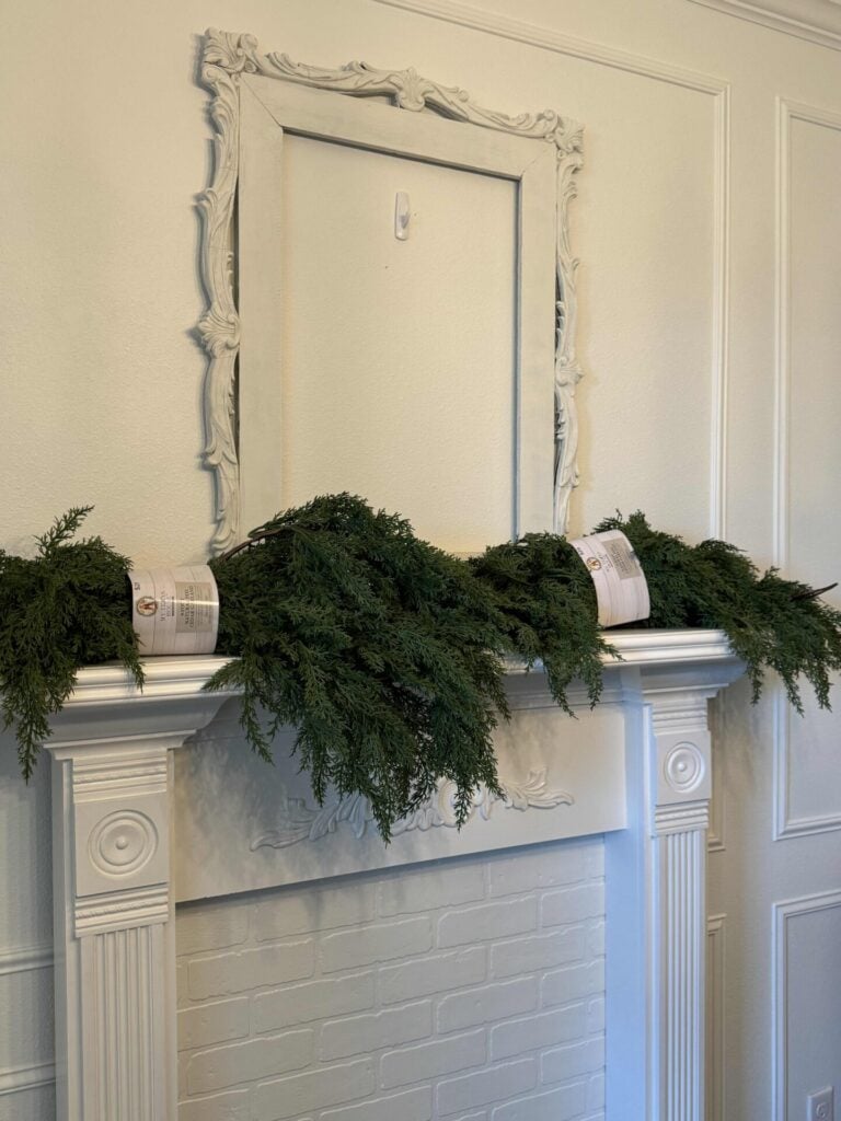 Two new evergreen garlands sitting on a mantel. 