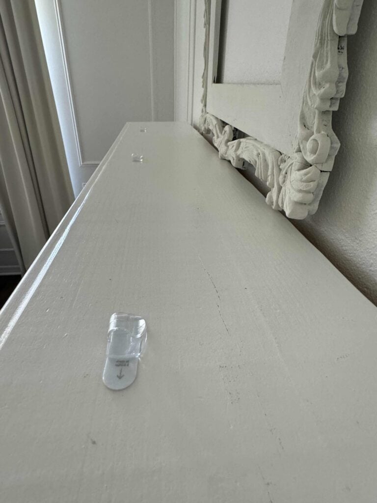 Three Command clips attached to the top of a mantel. 
