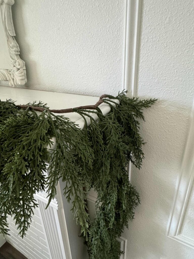 Tuck the Christmas garland behind the edge of the fireplace and let the excess hang down. 