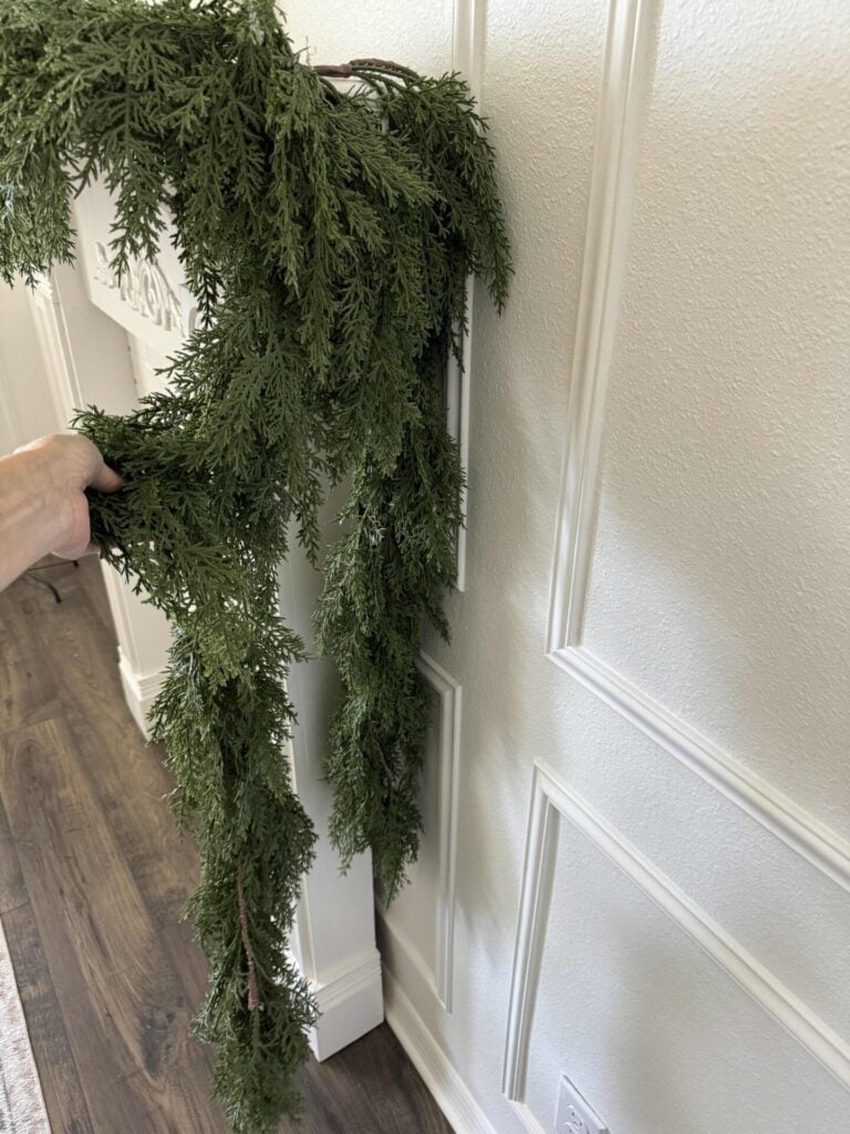 Two ends of the Christmas garland hang down the right side of the fireplace. 