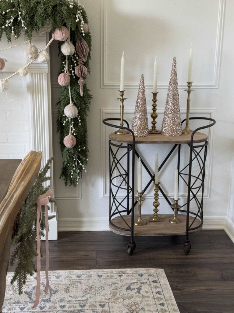 A bar cart next to a fireplace with a pretty garland hanging down. 