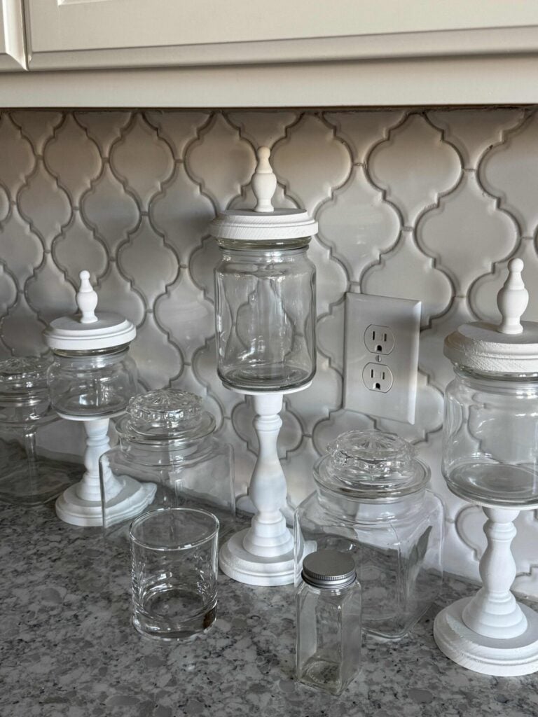 Lidded glass jars, a small glass cup, and an empty glass spice jar. 