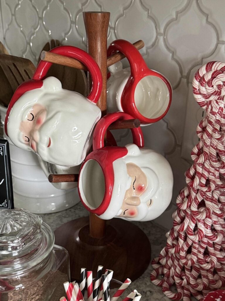 A wooden tree stand holding Santa mugs in a hot chocolate bar. 