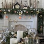 A table and mantel decorated with greenery and a New Year's Eve garland.