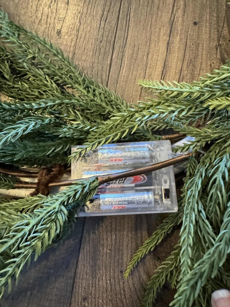 Fairy light battery pack attached to a DIY winter wreath. 