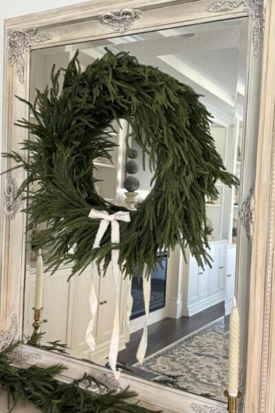 An evergreen wreath with white bow that was made from a Christmas garland.