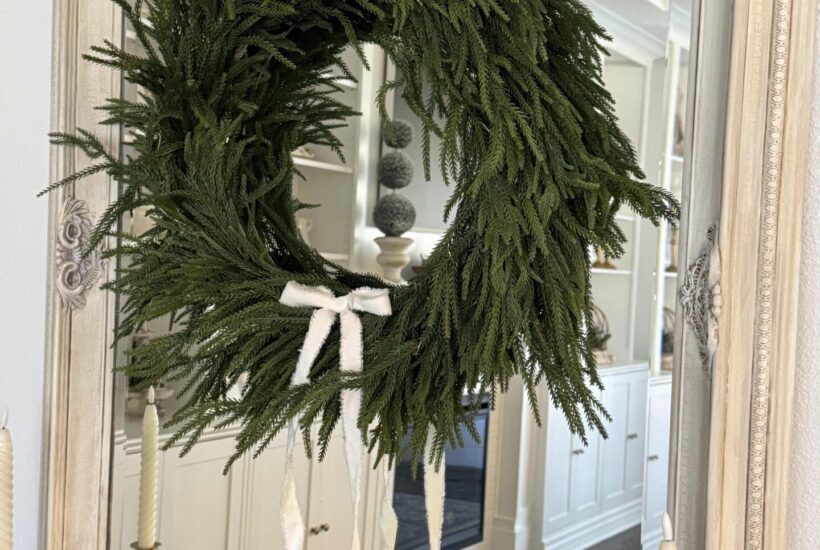 An evergreen wreath with white bow that was made from a Christmas garland.