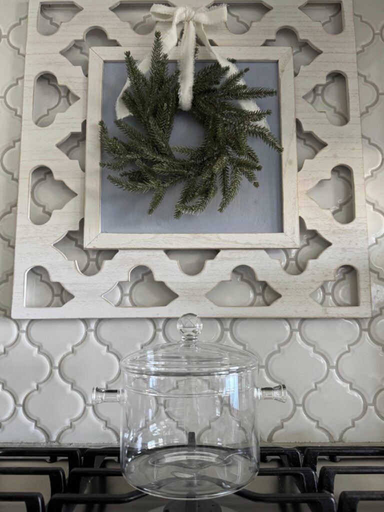 A glass simmer pot with lid sitting on a stove.