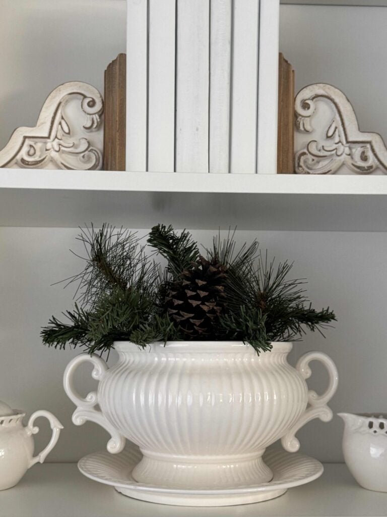 Evergreen pick in a soup tureen with a large pinecone. An easy winter decor idea to use after Christmas. 