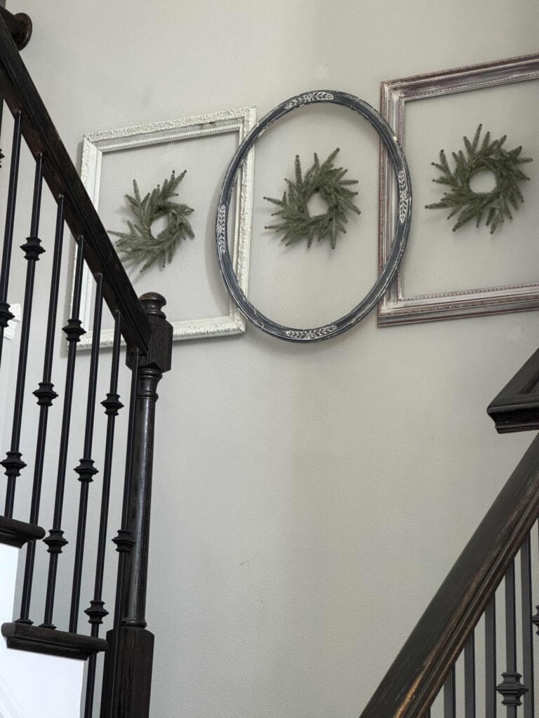 Three vintage frames on a wall with a mini wreath inside each one. 