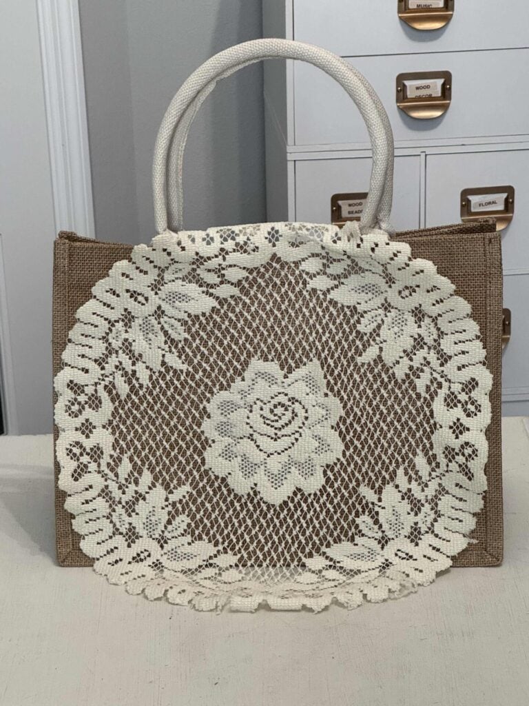 A lace doily laying on a burlap tote bag. 