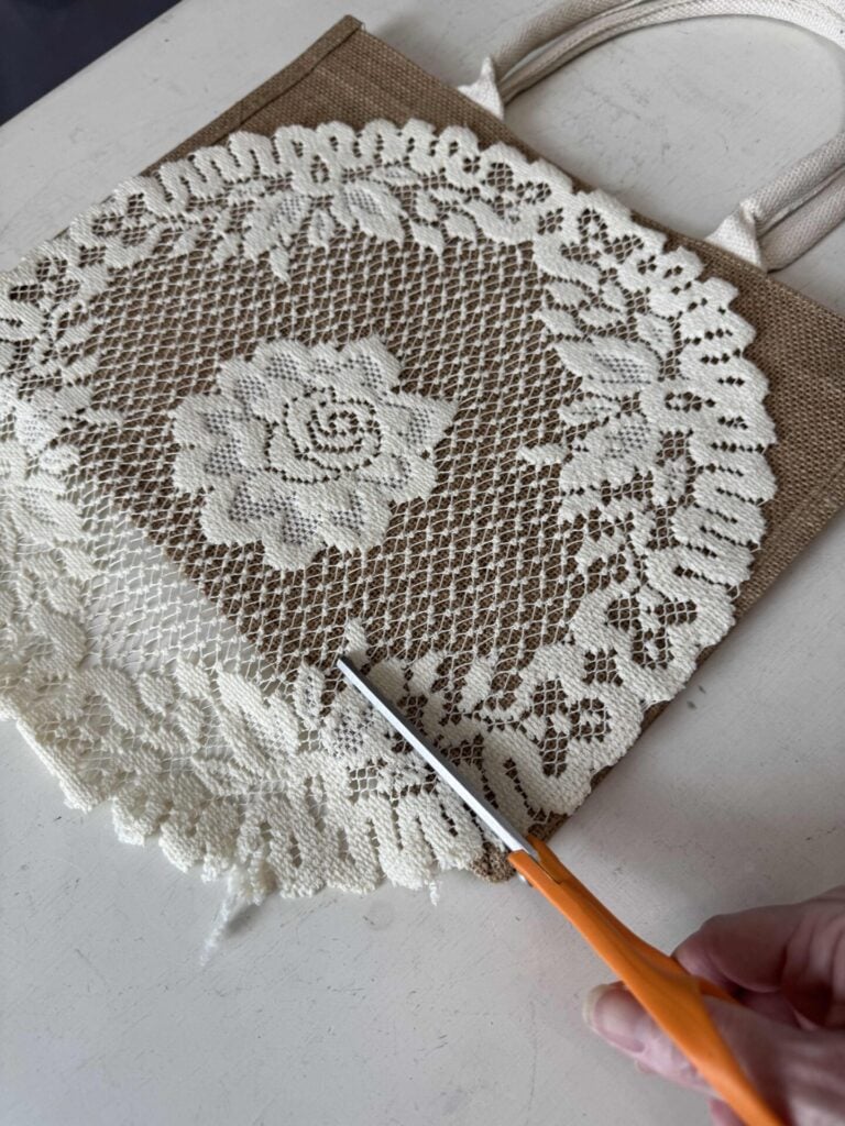 Someone cutting a lace doily with scissors. 