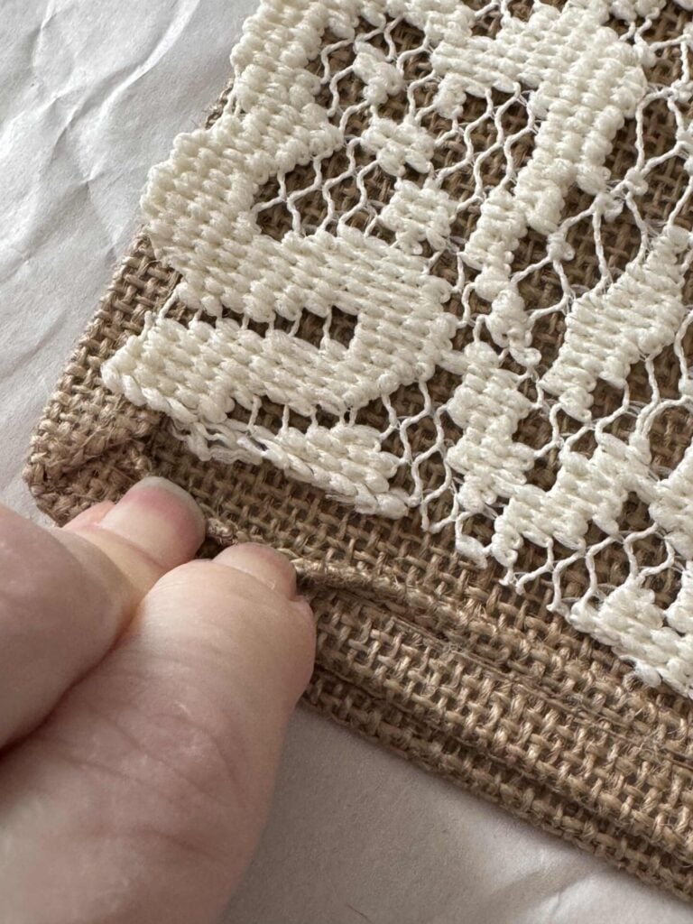 Someone pulling the seam beck on a burlap tote bag. 