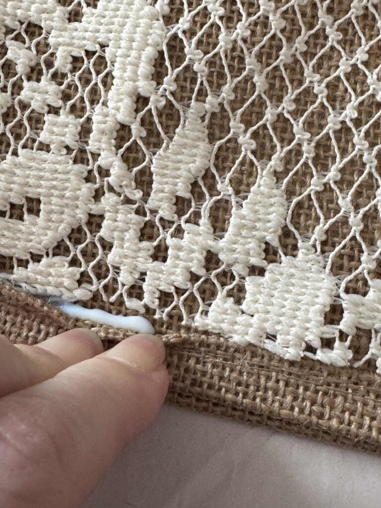 Someone putting glue in the seam of  a burlap tote bag. 