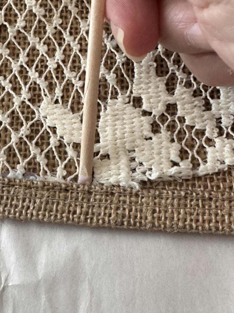 Someone pressing a doily into a burlap seam. 