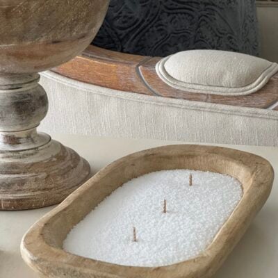 A DIY candle in a bowl made with white sand candle wax and three wicks.