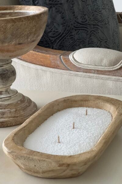 A DIY candle in a bowl made with white sand candle wax and three wicks.