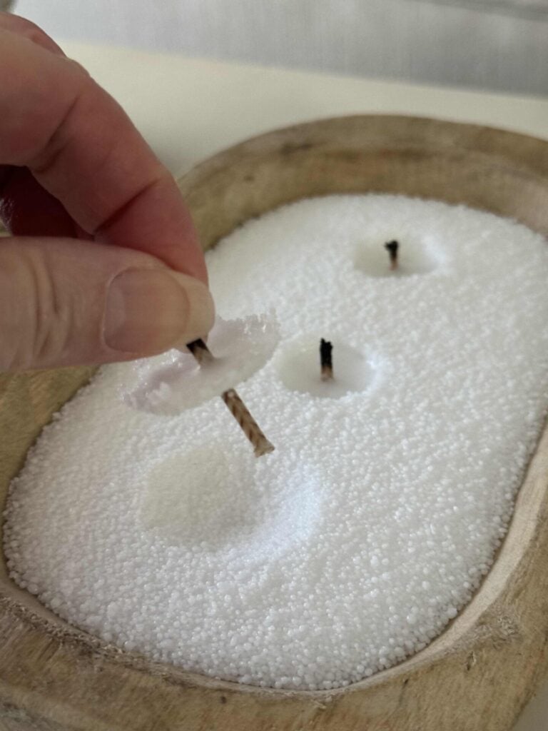 Someone holding a wick they pulled out of a DIY three wick white candle.