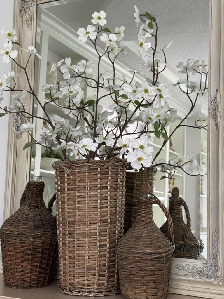 White dogwood branches inside a tall basket with a demijohn on either side makes great spring living room decor.