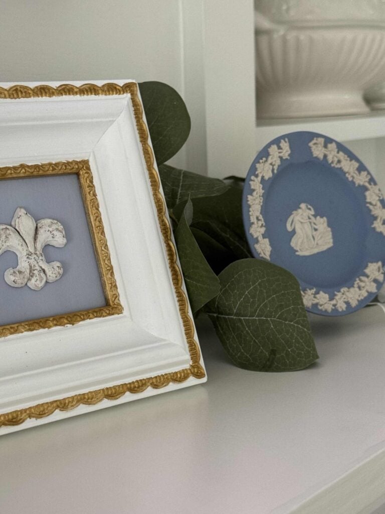 Blue and white DIY art and a blue Wedgewood saucer displayed on a mantel.  