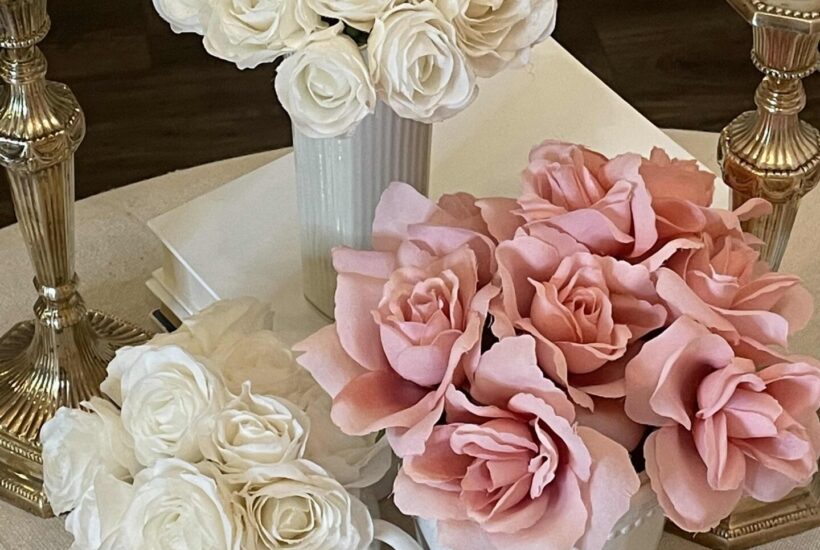 A Valentine's table with three vases of roses and a heart garland.