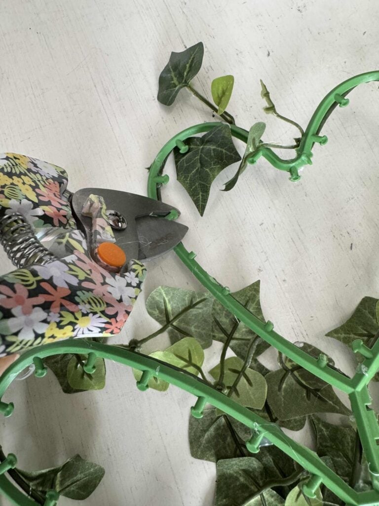 Someone using pruners to cut plastic tips off a shamrock form. 