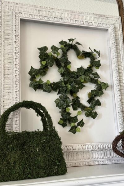 A DIY St Patrick's Day shamrock wreath made with Ivy and moss on a white frame.