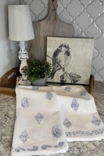 DIY block print kitchen towels laying over a tray on a kitchen counter.
