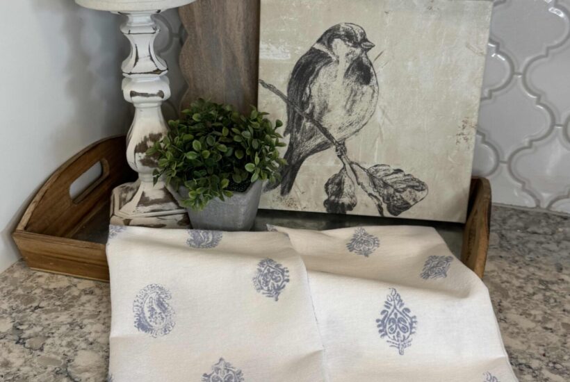 DIY block print kitchen towels laying over a tray on a kitchen counter.