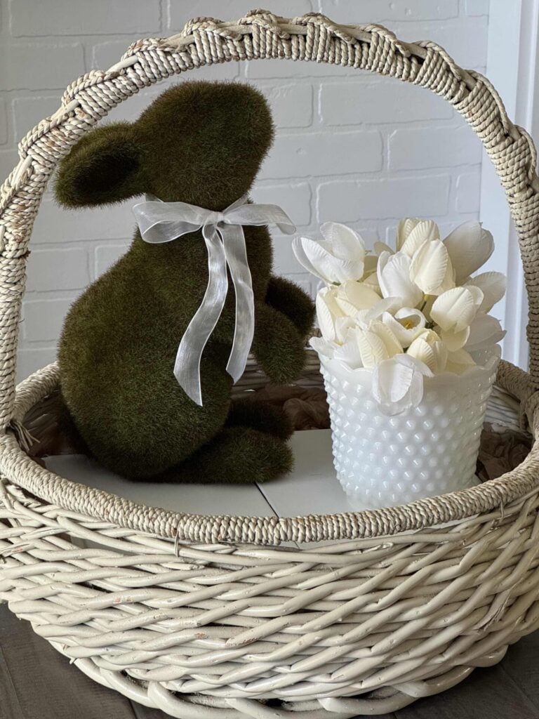 A white vintage basket with a moss bunny and milk glass bowl with tulips inside.