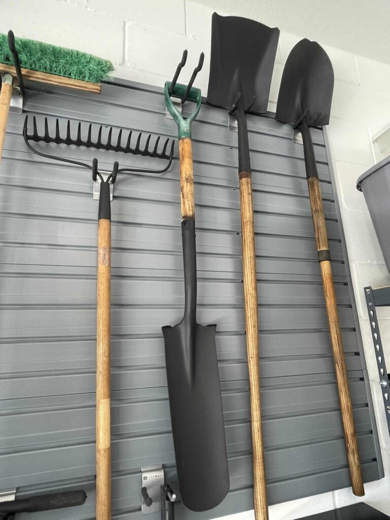 Clean and sharpened yard tools hanging on a garage wall system. 