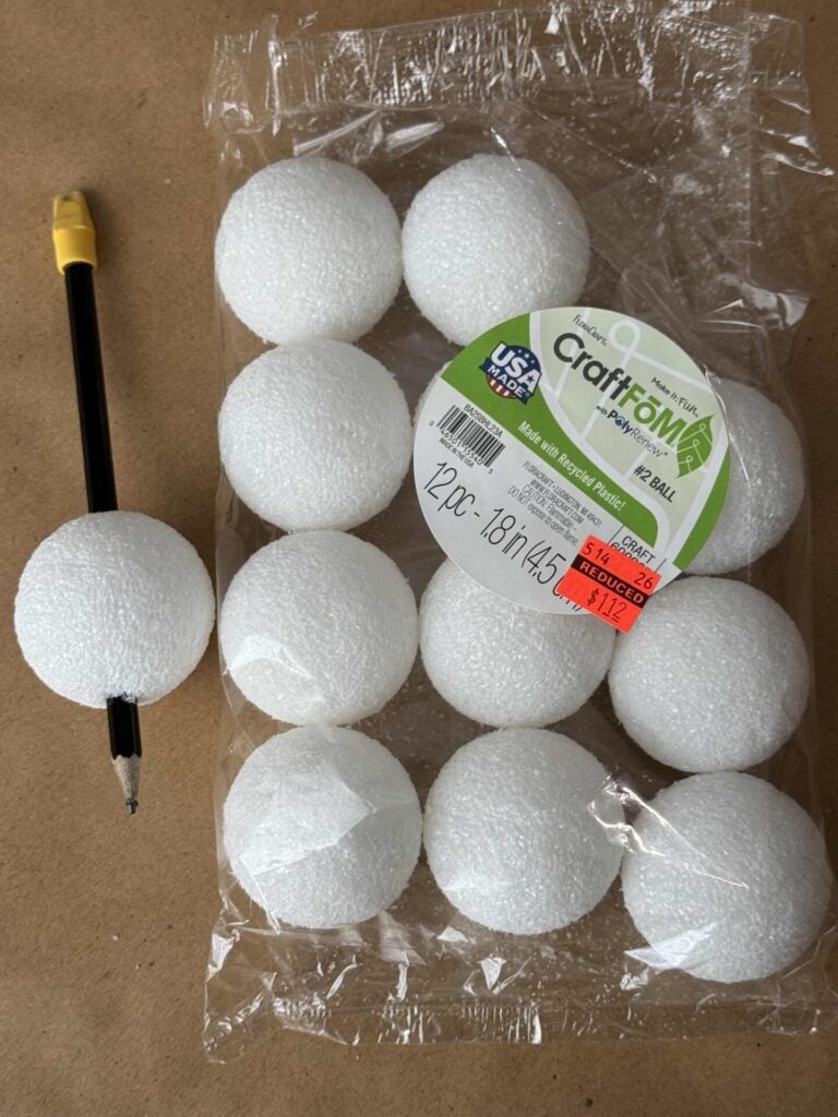 A bag of discounted styrofoam balls. One ball has a pencil pushed through it. 