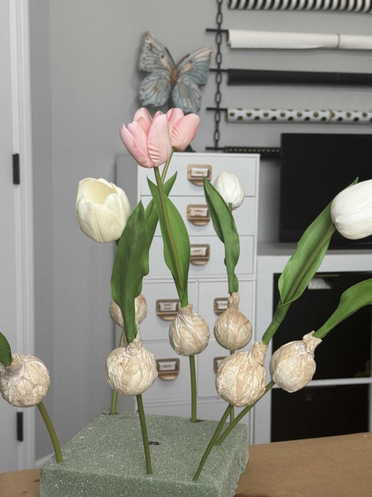 Tulips with faux bulbs drying on a piece of square foam. 