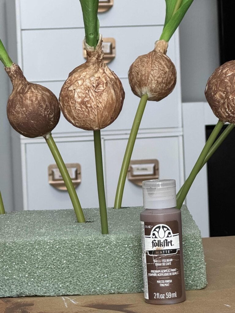 Faux tulip bulbs painted brown with a bottle of FolkArt paint. 