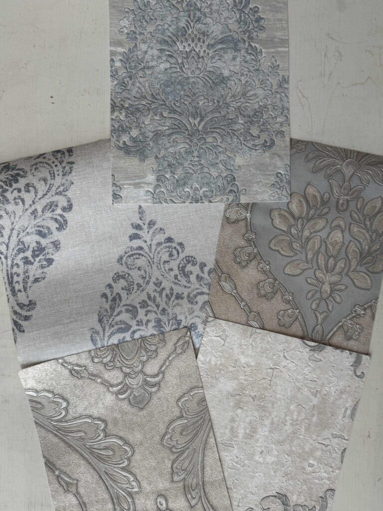Five wallpaper samples laying on a desk. 