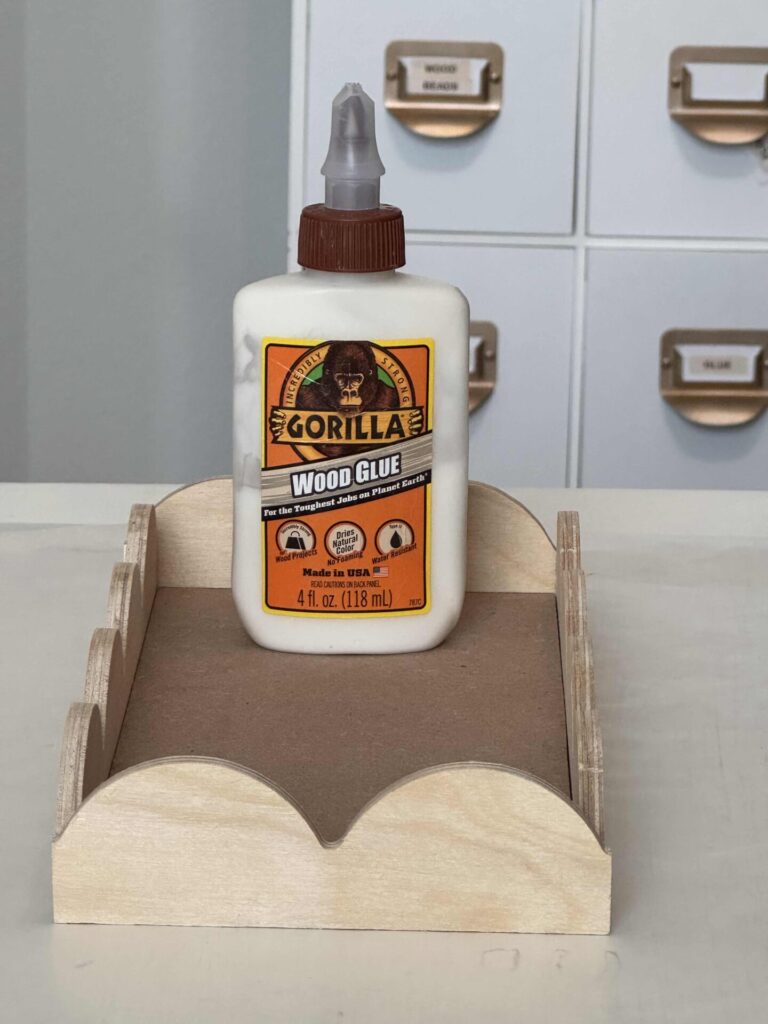 A DIY scalloped wood tray with a bottle of wood glue on it. 