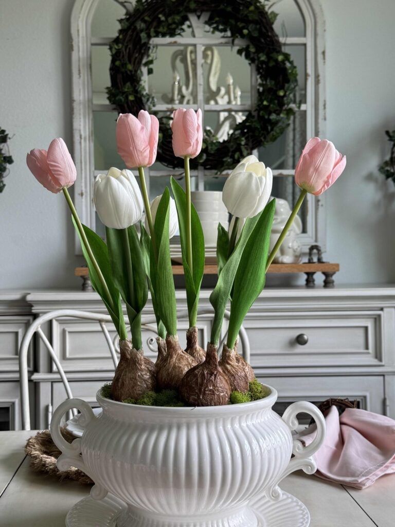 A DIY tulip bulb arrangement on a table with a buffet in the background. 