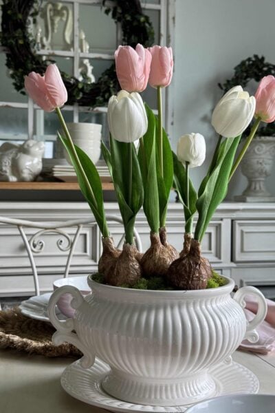 Pink and white faux tulip bulbs arranged in a white soup tureen.