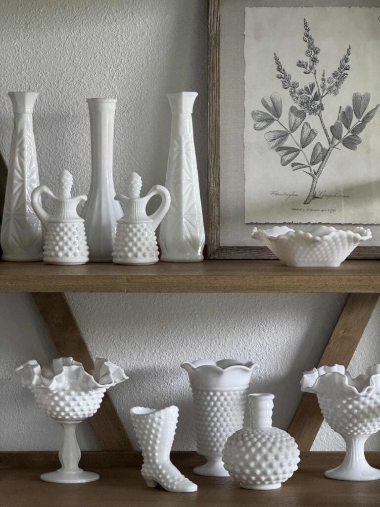 Spring kitchen decor idea #3 is to add a white milk glass collection and a framed picture to shelves. 