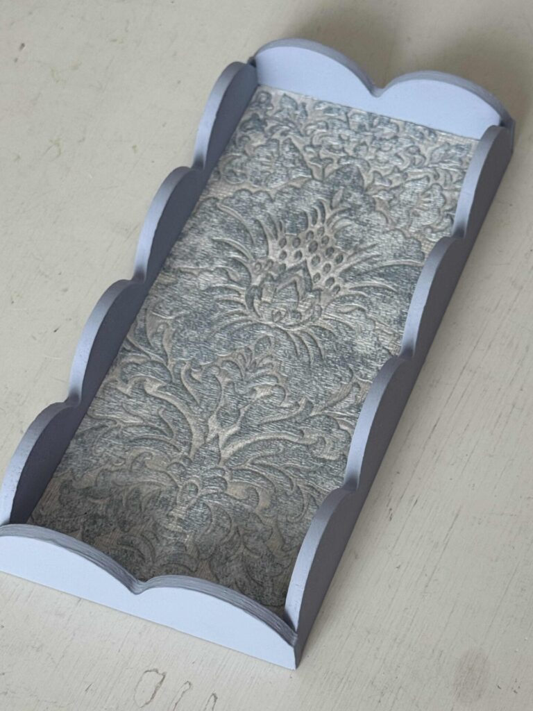 A blue DIY scalloped wood tray lined with a wallpaper sample. 