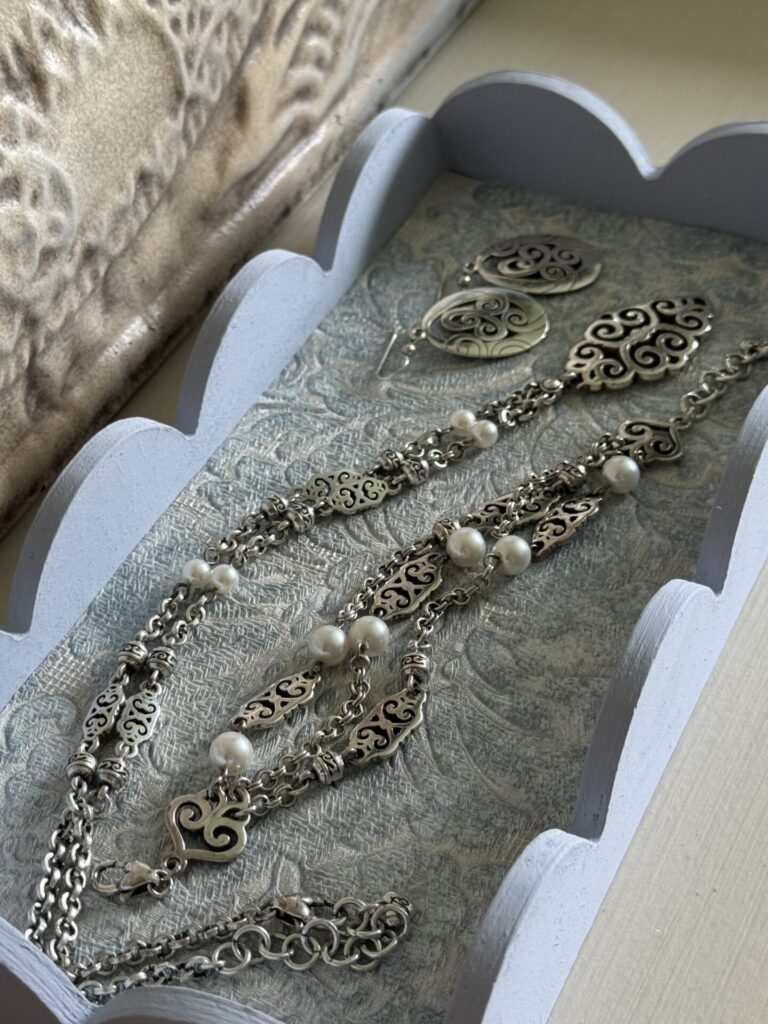 A blue DIY scalloped tray holding silver and pearl jewelry. 