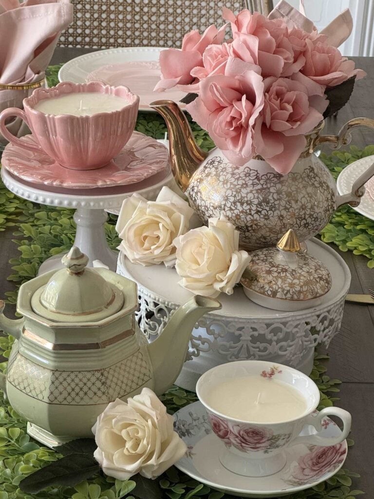 DIY teacup candles in a centerpiece with vintage teapots and faux roses.
